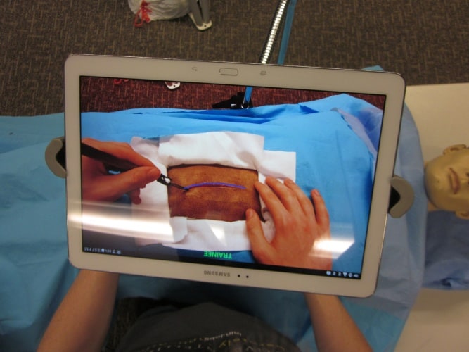 The system uses a transparent display with a tablet positioned between the surgeon and the operating field. 