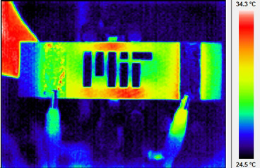 Infrared themographic image of a nanoengineered composite heated via electrical probes (clips can be seen at bottom of image). The scalebar of colours is degrees Celsius. The MIT logo has been machined into the composite, and the hot and cool spots around