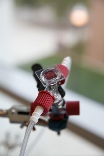 Prototype aqueous solar flow battery under development at The Ohio State University. The square piece of solar cell (centre) is red, because the researchers are using a red dye to tune the wavelength of light it absorbs and converts to electrons.