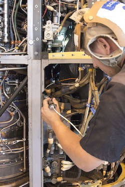 Aviation Mechanic Cody Schwarz works to install a 3D printed, titanium link and fitting on an MV-22 Osprey engine nacelle 