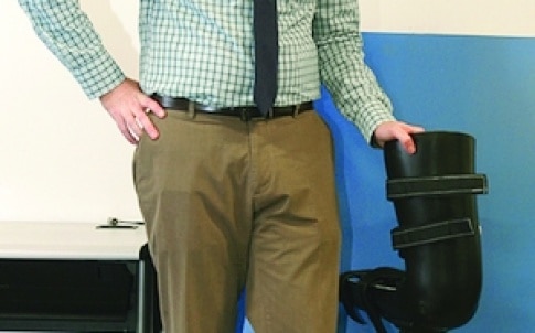 Dr Robert Gregg stands next to a robotic leg that was designed by UTDesign students and is similar to the one reported in his research