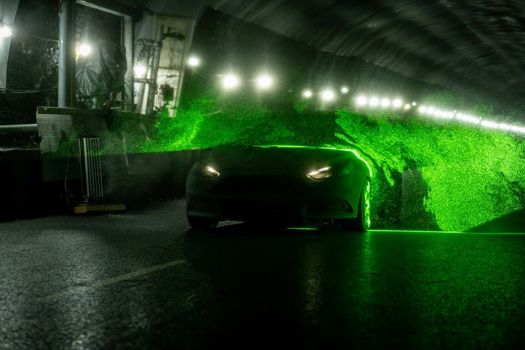 A car drives through a sheet of helium-filled soap bubbles illuminated with a laser