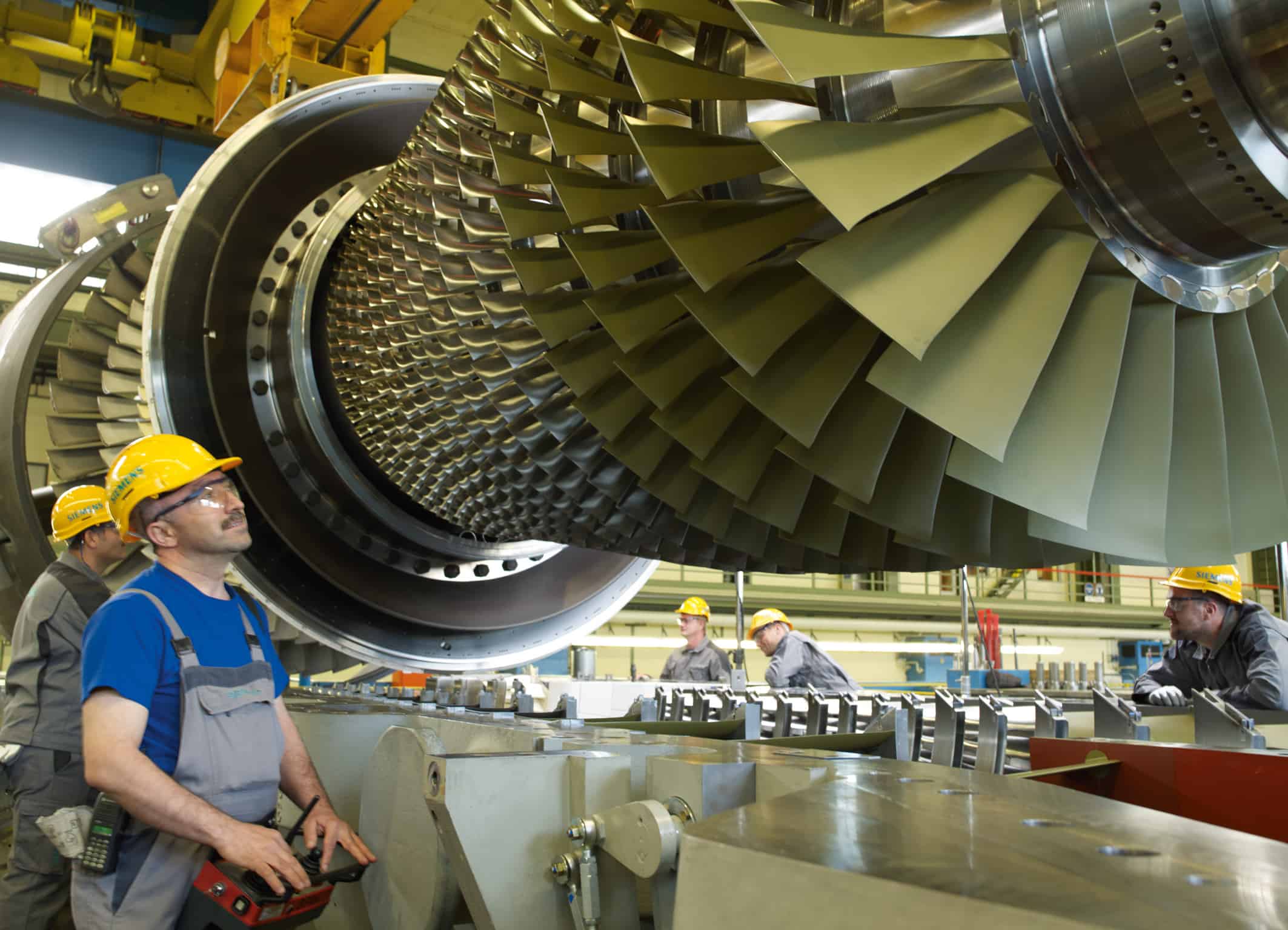 Das Bild zeigt Siemens-Mitarbeiter in der Endmontage beim Einlegen eines Turbinenläufers der Siemens Gasturbine SGT5-4000F. The picture shows Siemens employees in the final assembly hall in the Berlin manufacturing plant while inserting a turbine rotor of the Siemens gas turbine SGT5-4000F.