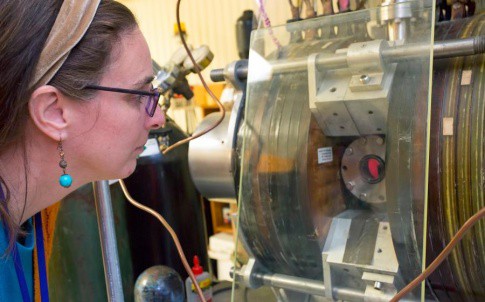 Lenore Rasmussen examines a titanium coupon used in her synthetic muscle being treated in an oxygen plasma at PPPL