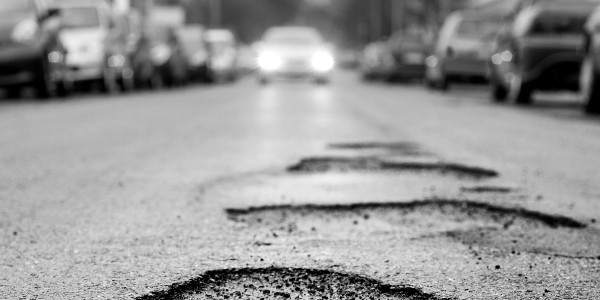 Broken asphalt resulting in a pothole, dangerous to motorists. Selective focus, low-angle view