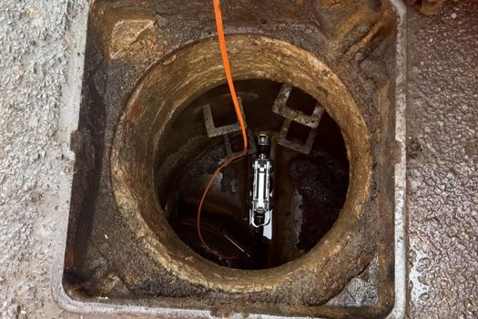 The Minicam crawler robot being lowered into the sewer pipe