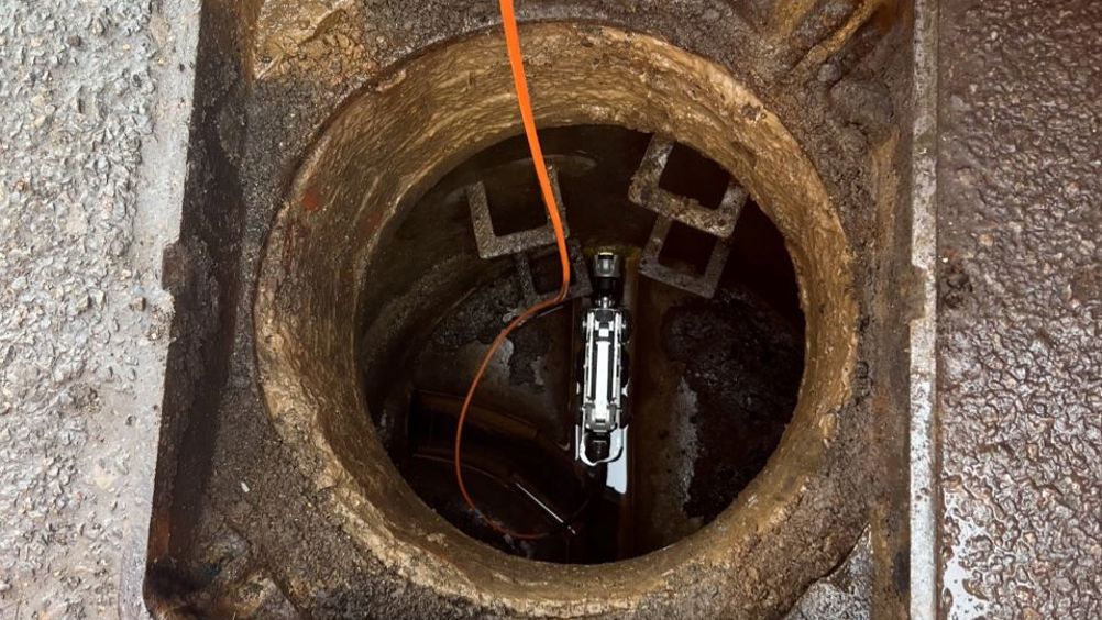 The Minicam crawler robot being lowered into the sewer pipe