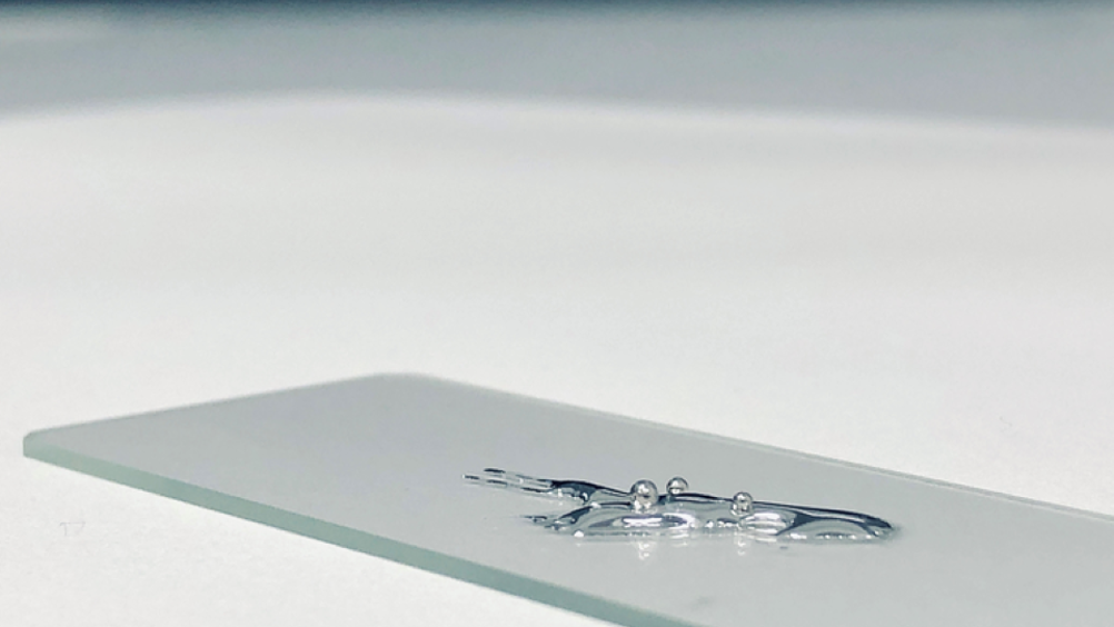 Liquid gallium and three solid beads of platinum, demonstrating the dissolution process of platinum in gallium described in the research paper