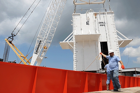 Crewmen aboard the motor vessel Joe Griffin guide a cofferdam onto the deck. The chamber is designed to contain the oil discharge before it reaches the surface.