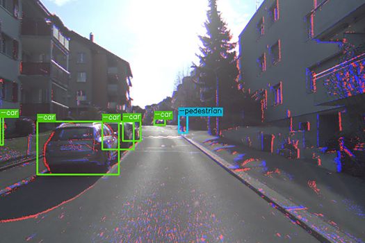 Image shows colour information from the colour camera and events (blue and red dots) from the event camera; bounding boxes show the detection of cars by the algorithm
