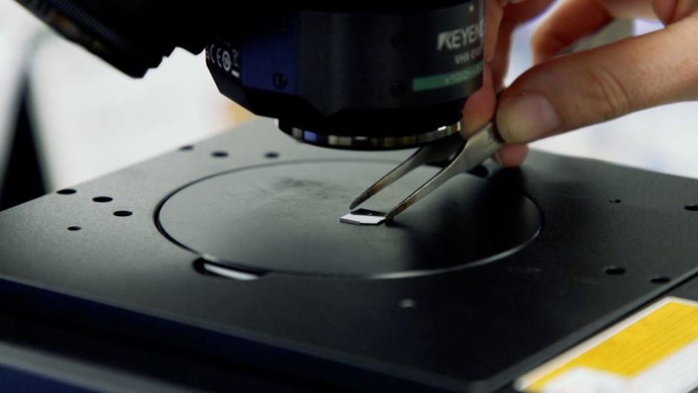 The chip bearing the image of ‘the world’s smallest violin’ is positioned under a microscope. The intricate structure is only visible at high magnification